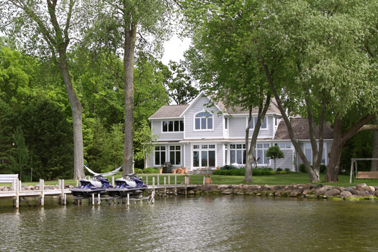 Luxury home with lawn on the lakefront with jet skis